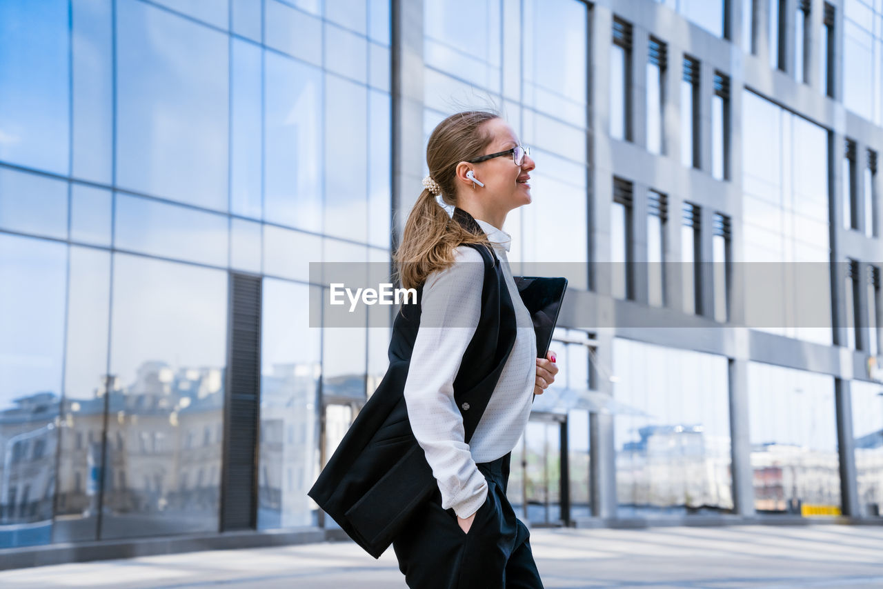 Portrait of successful business woman in stylish suit using laptop posing next