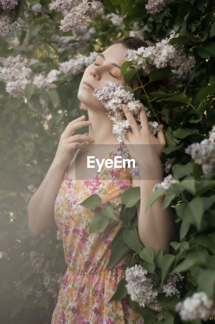 Midsection of woman standing by flowering plants