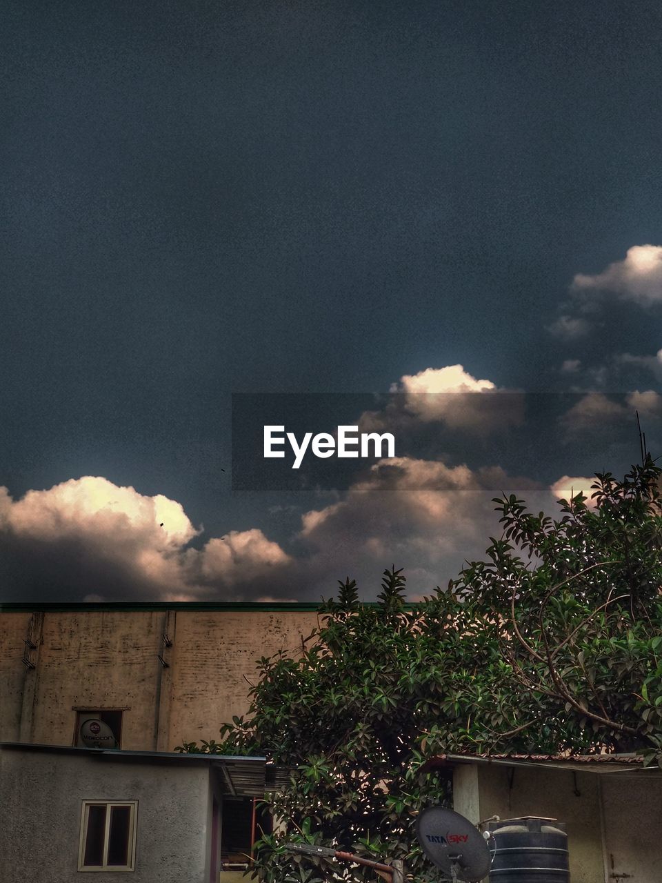 LOW ANGLE VIEW OF HOUSES AGAINST STORM CLOUDS