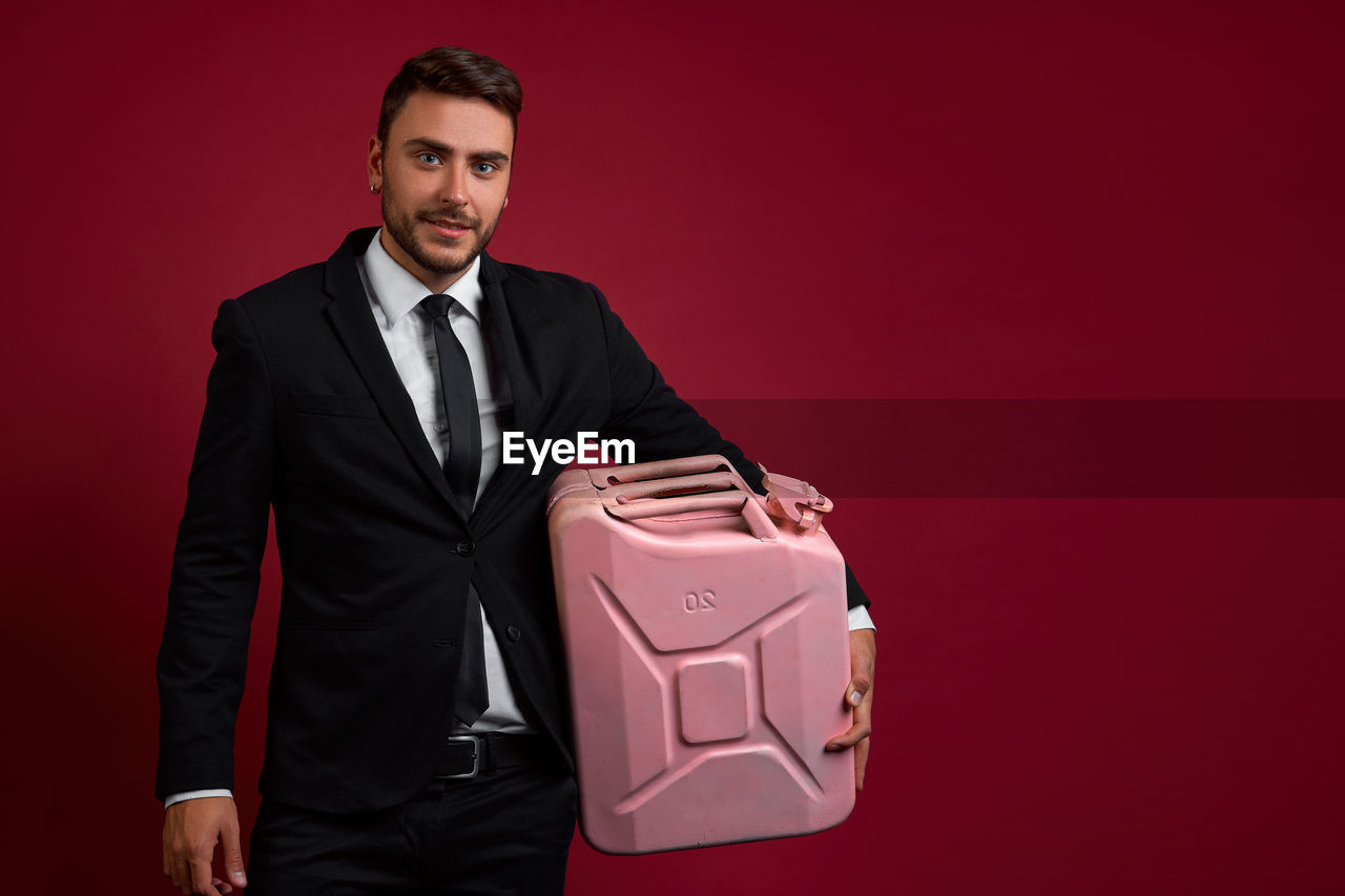 PORTRAIT OF YOUNG MAN WEARING RED MASK AGAINST GRAY BACKGROUND