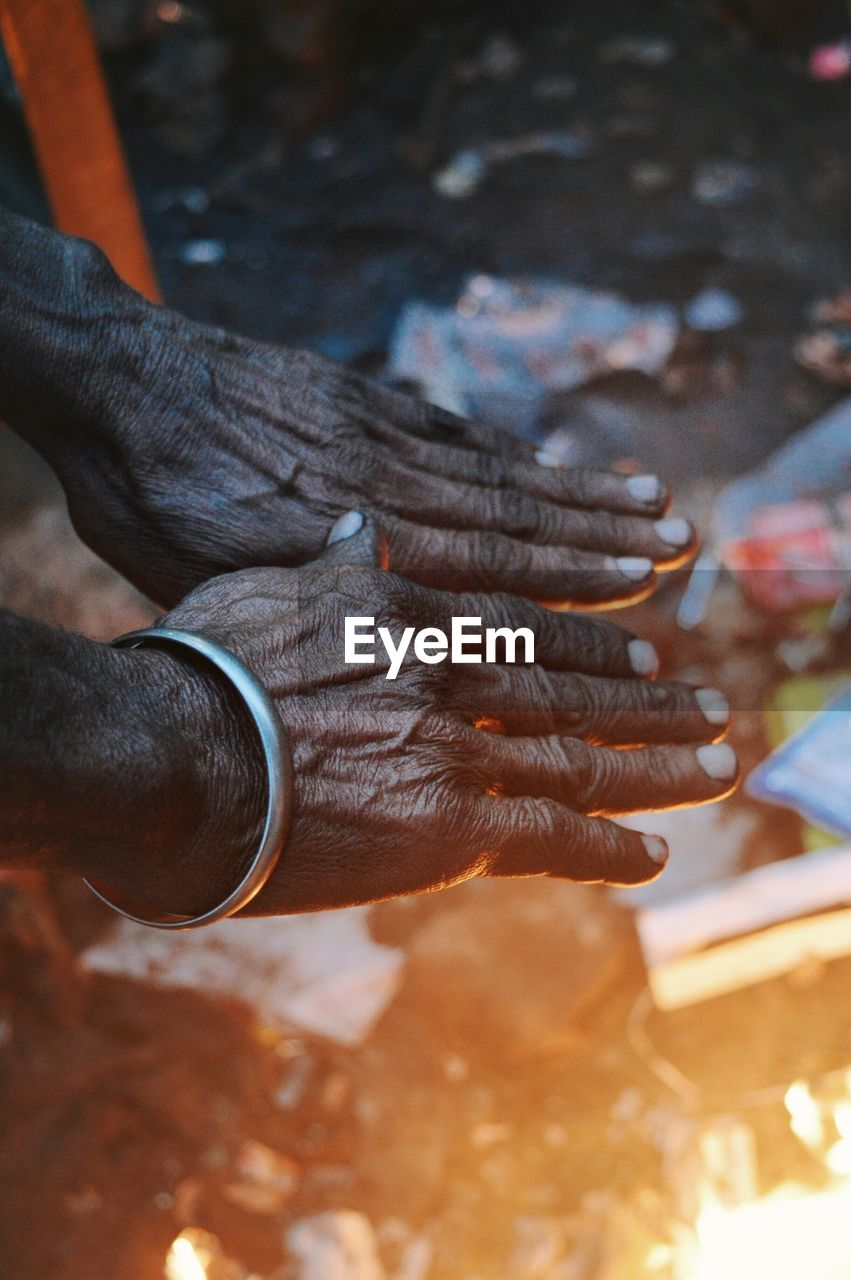 Cropped image of hands warming over bonfire