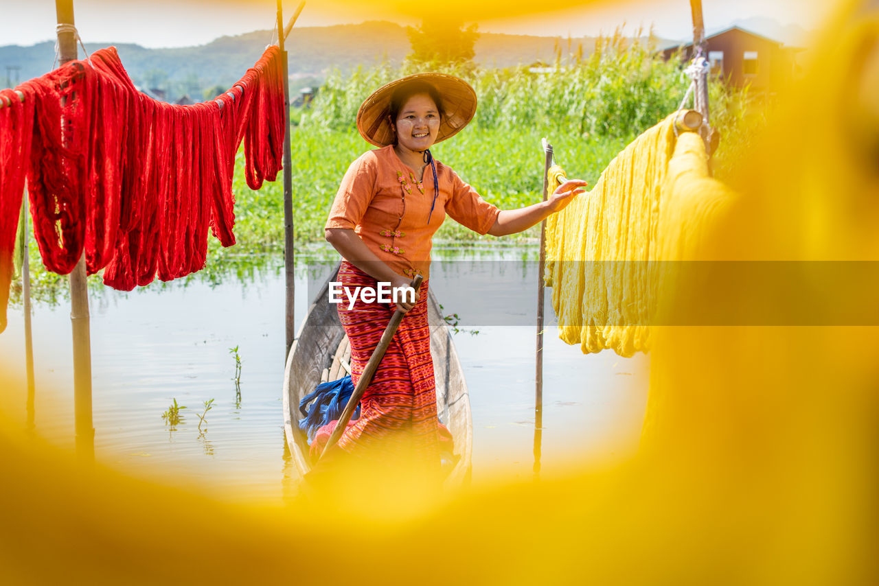 PORTRAIT OF A SMILING YOUNG WOMAN STANDING AGAINST YELLOW WALL