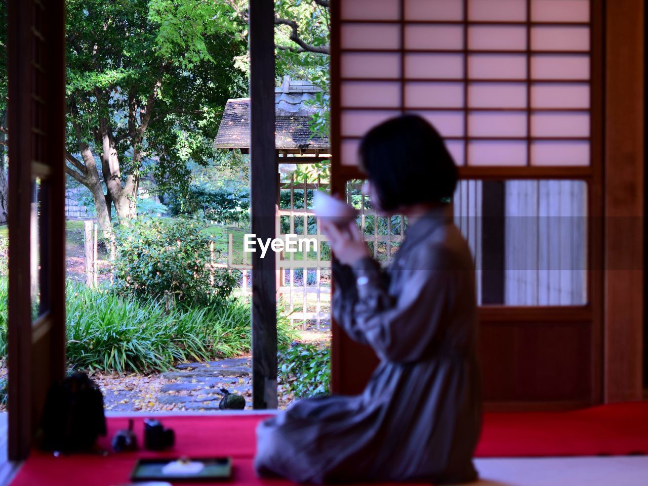 Side view of woman sitting on window