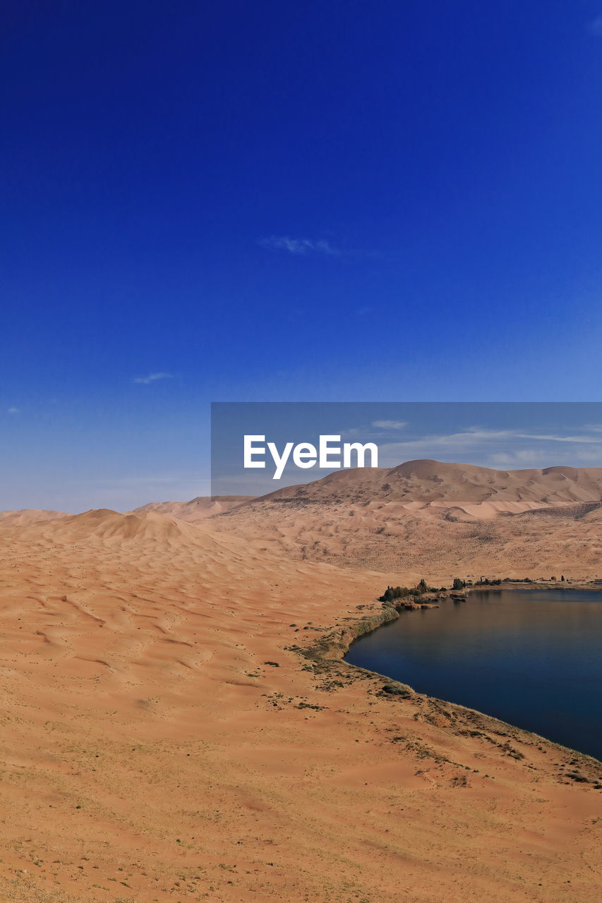 SCENIC VIEW OF ARID LANDSCAPE AGAINST BLUE SKY