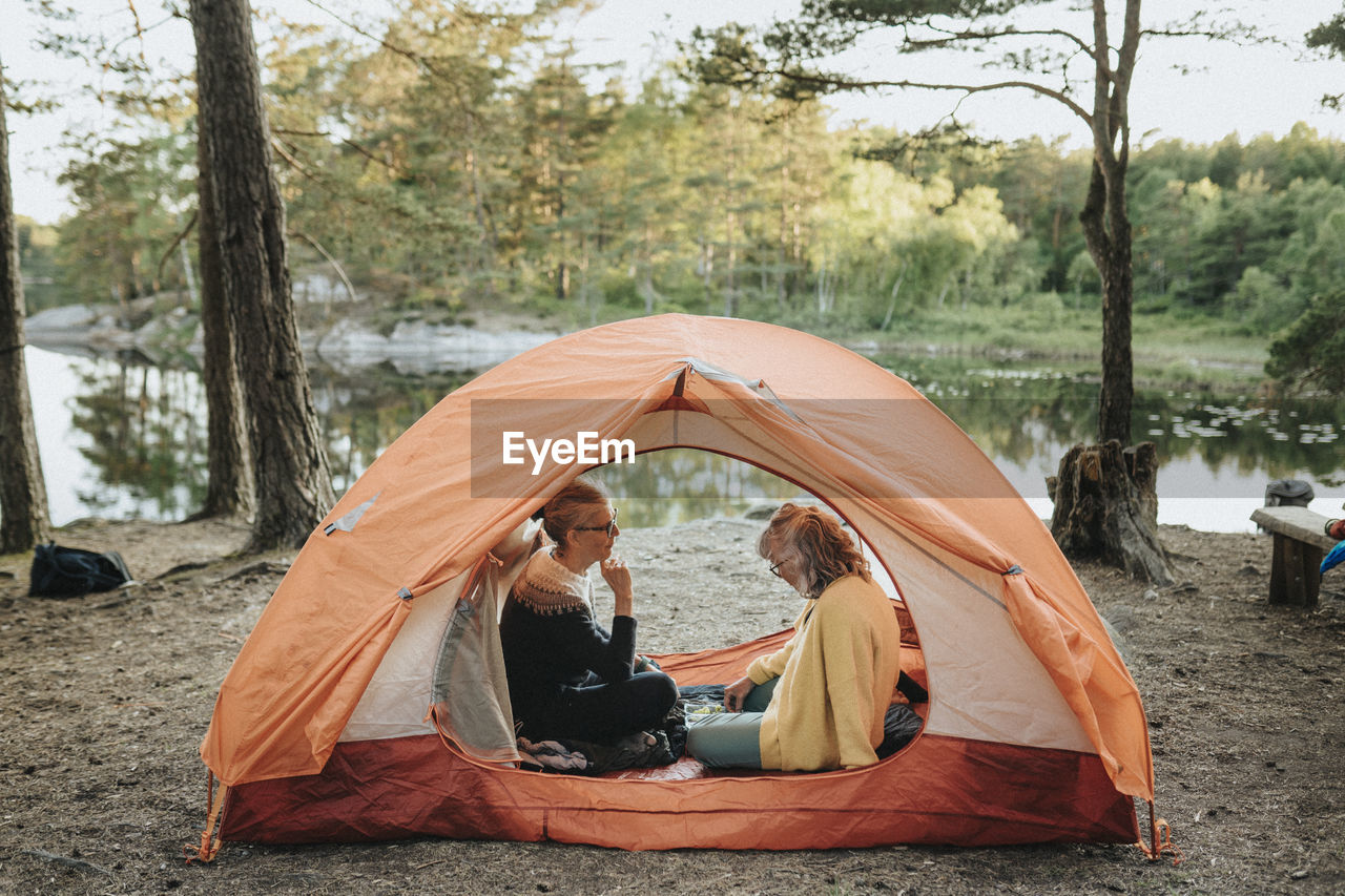 Two senior women sitting in tent at campsite