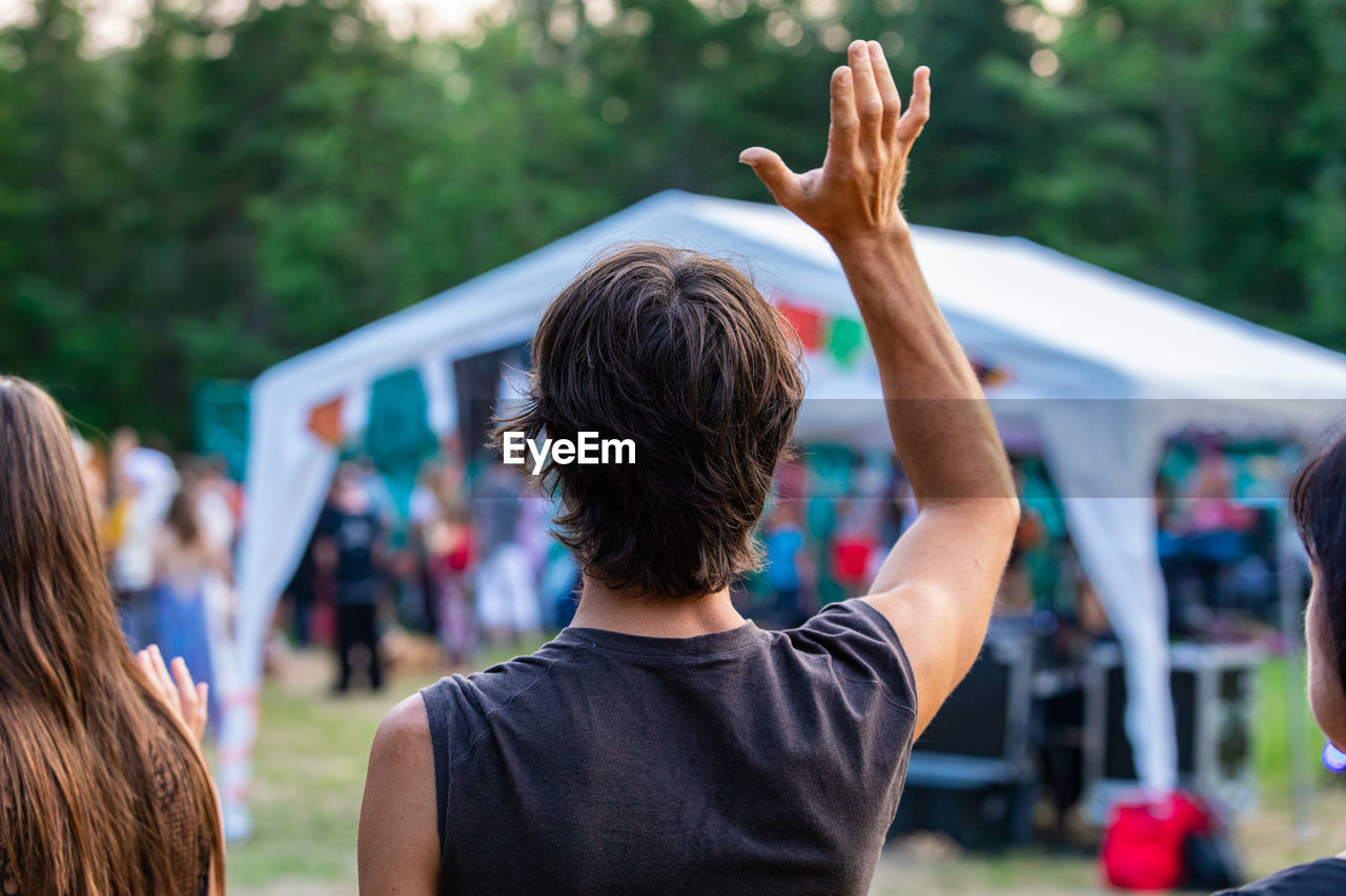 REAR VIEW OF PEOPLE ENJOYING IN MUSIC FESTIVAL