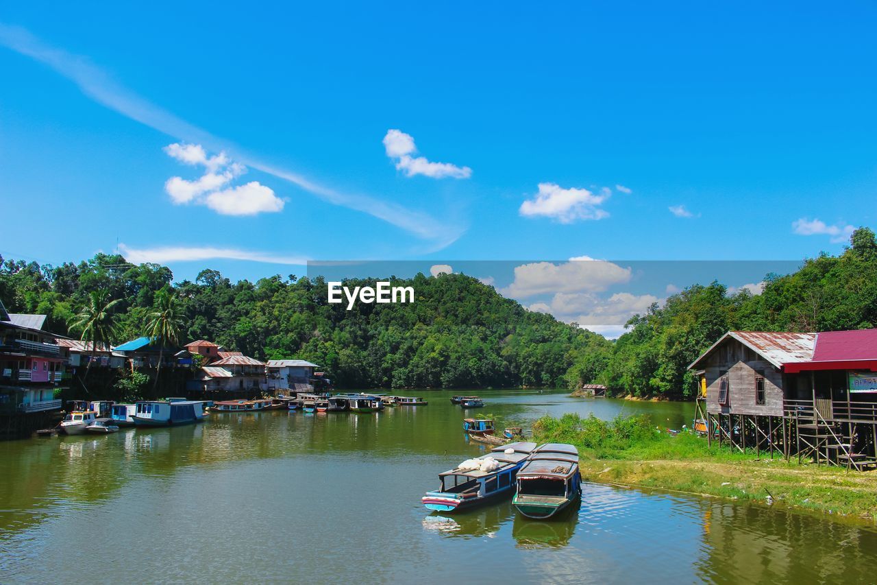 Boats moored on lake by buildings against sky