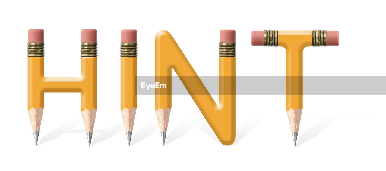 Yellow wooden pencils formed to spell hint word over white background