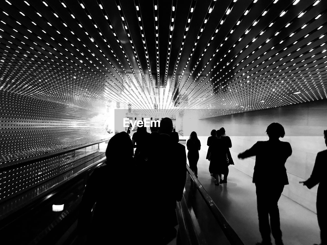 Silhouette people in illuminated tunnel