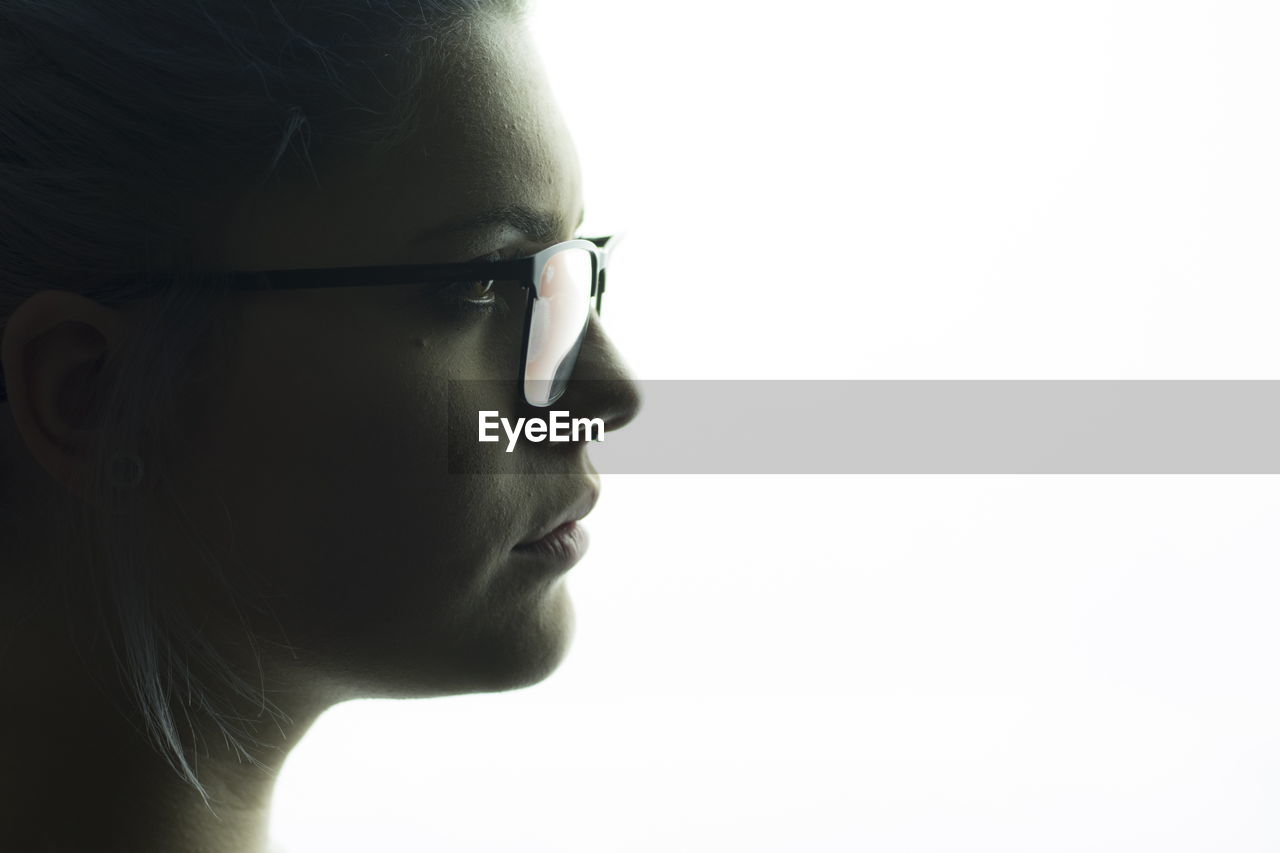 Close-up of young woman looking away against white background