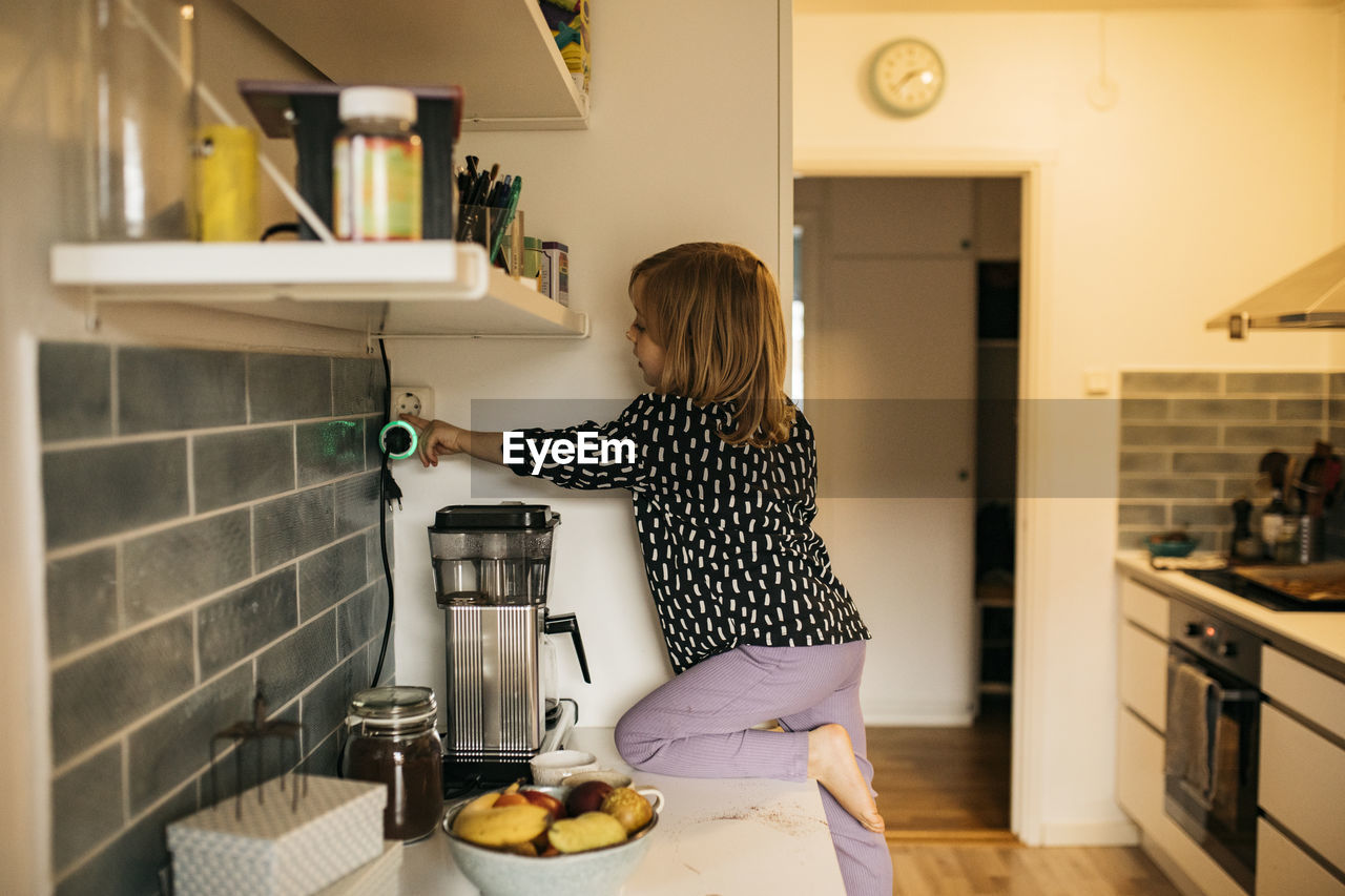 Woman touching plug in electric socket