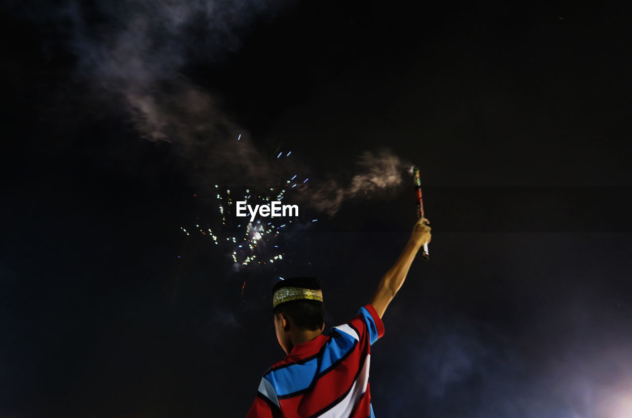 Low angle view of lit firework against sky at night