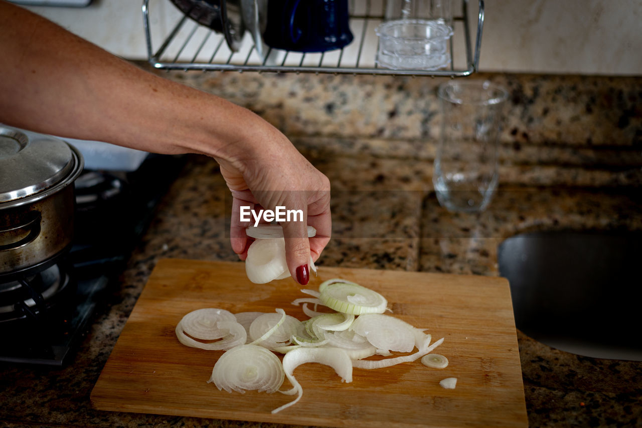 Hand holding sliced onions on a cutting board. food seasoning.