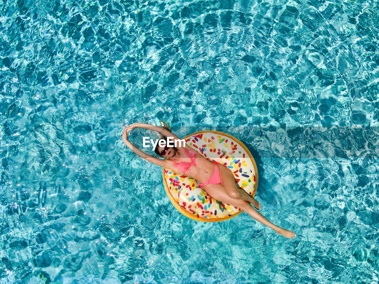 Directly above shot of woman on pool raft floating in swimming pool