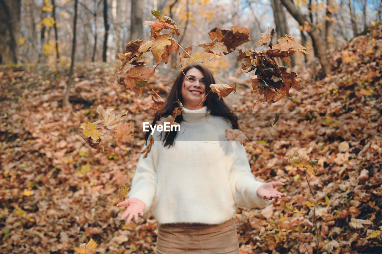 Full length of a young woman in autumn leaves