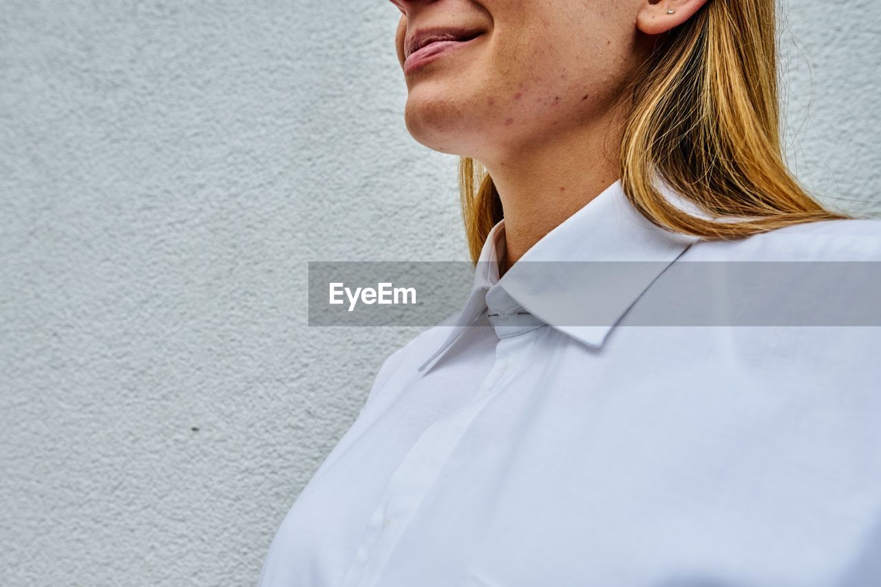 Midsection of woman standing against white wall