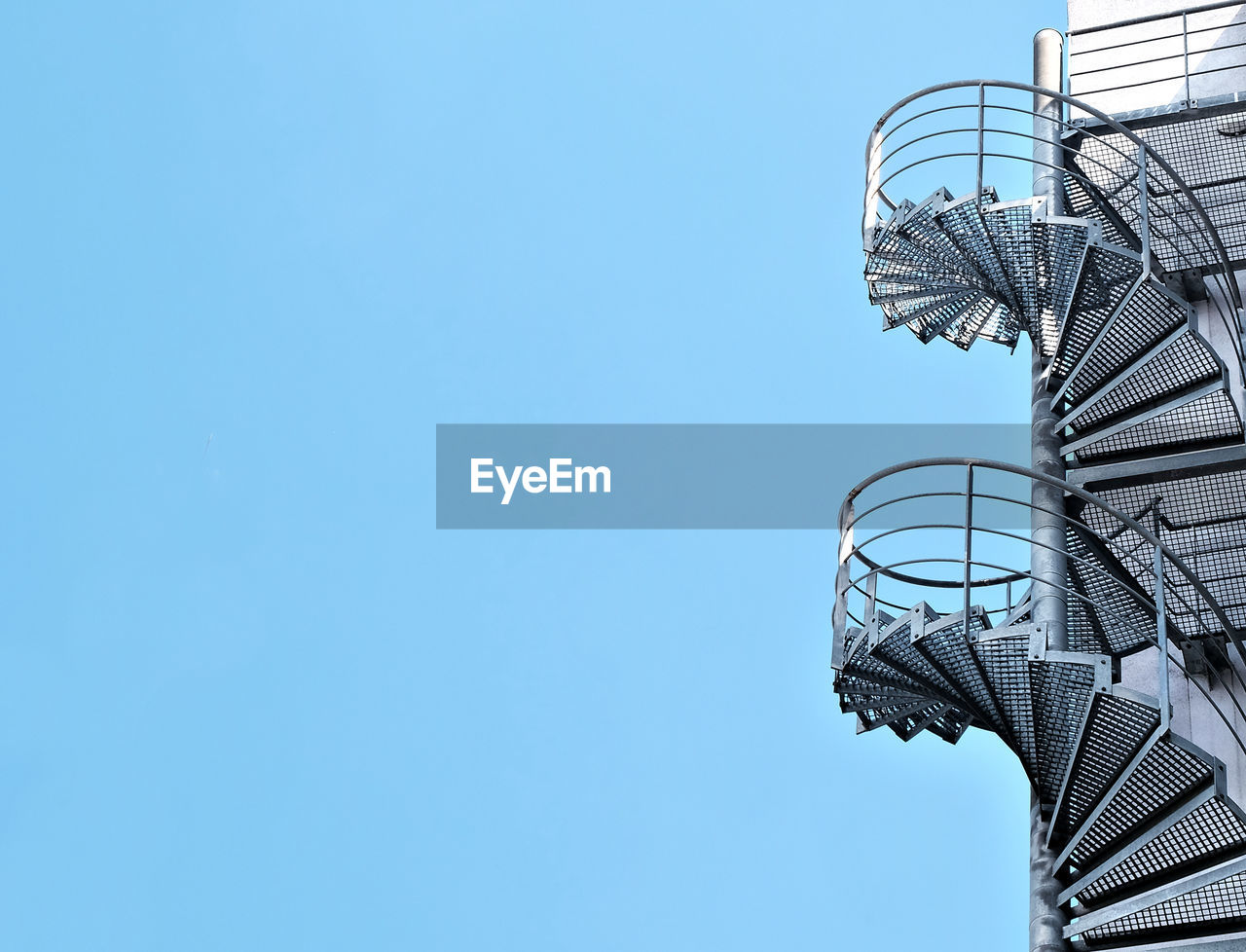 Low angle view of spiral staircase against clear blue sky