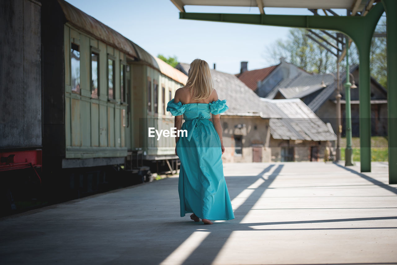 Rear view of woman walking on railroad station platform by train