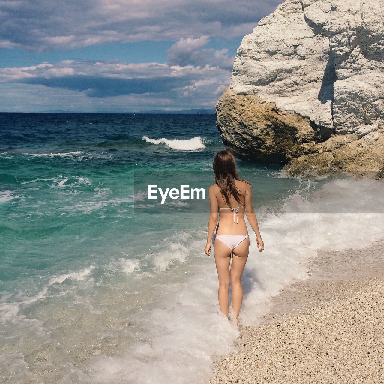 Rear view of young woman in bikini standing at beach