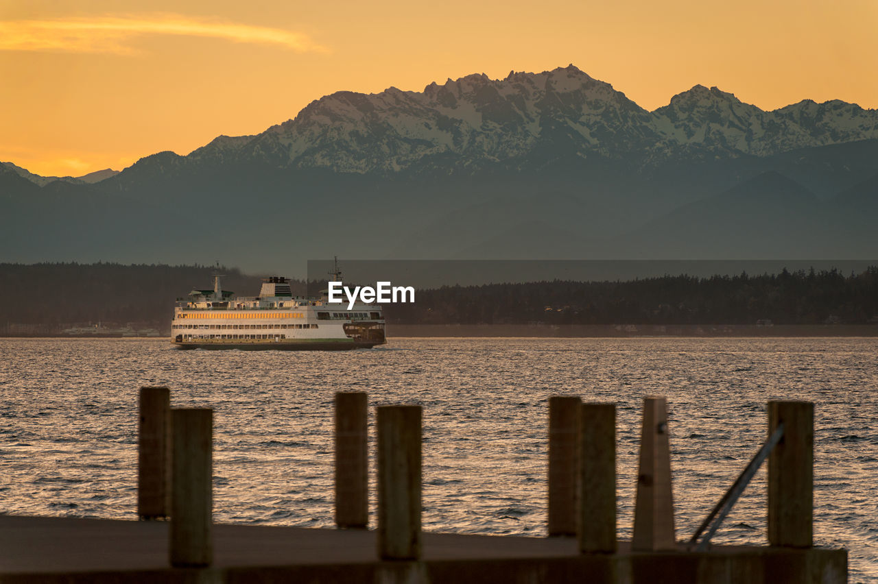 Ferry boat in puget sound against mountain during sunset