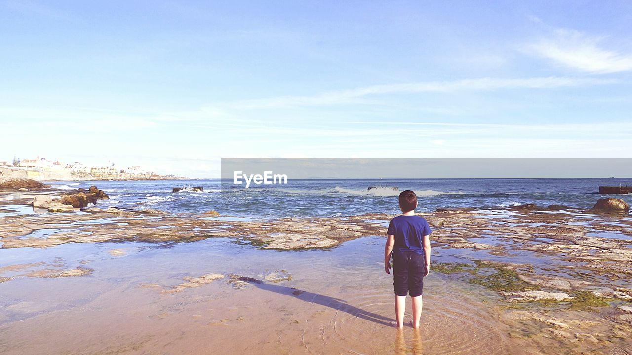 Rear view of boy standing on beach