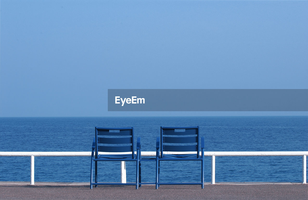 Deck chairs blue on beach against clear blue sky