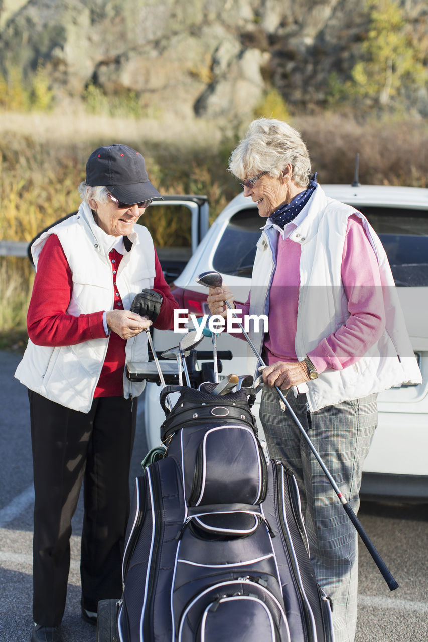 Happy senior women selecting golf clubs from bag