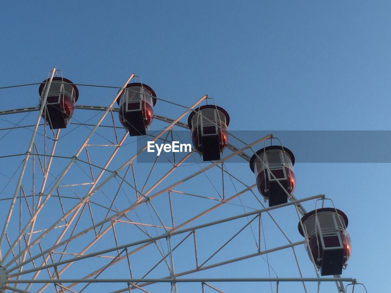 Low angle view of ferris wheel against clear blue sky