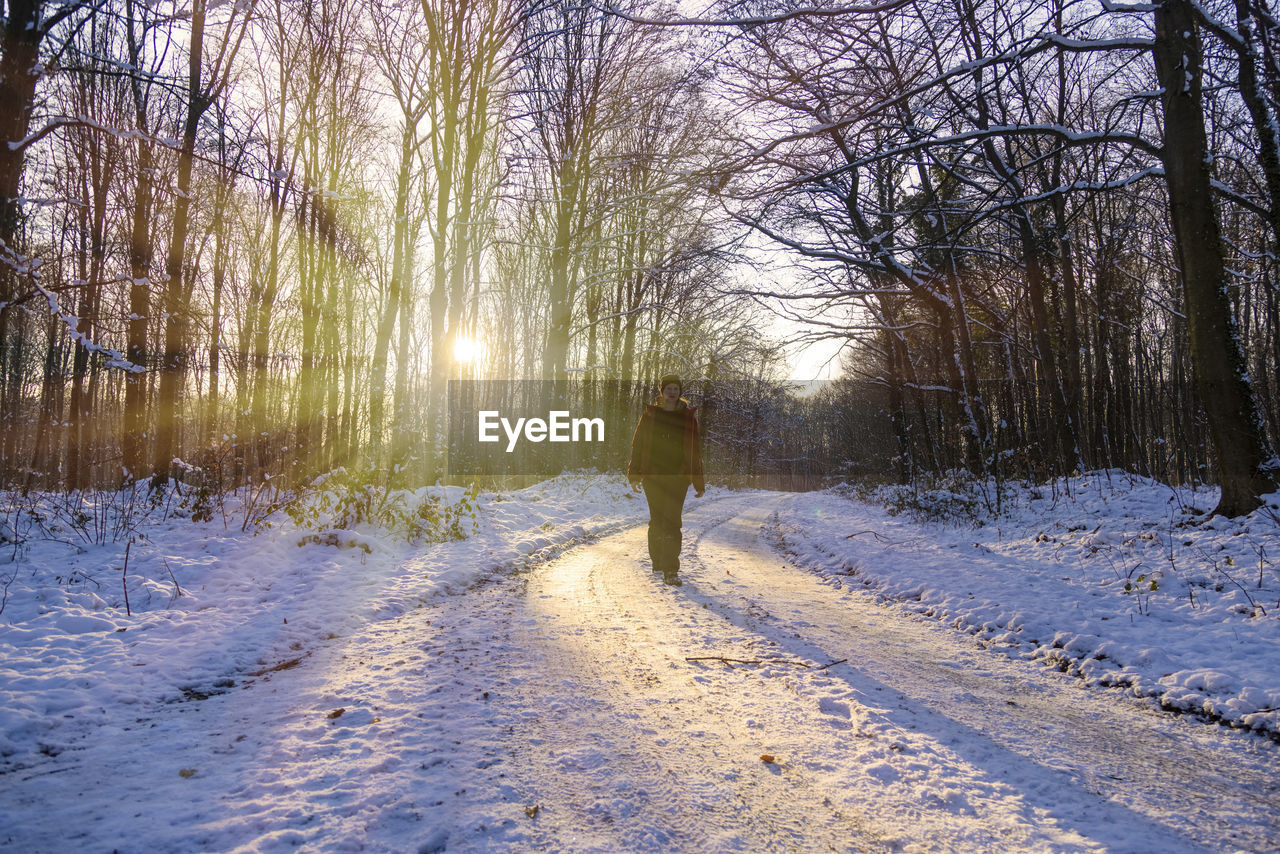 REAR VIEW OF PERSON STANDING BY SNOW COVERED LAND