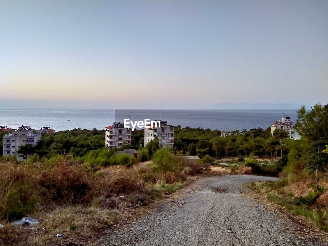 ROAD AMIDST BUILDINGS AND SEA AGAINST CLEAR SKY