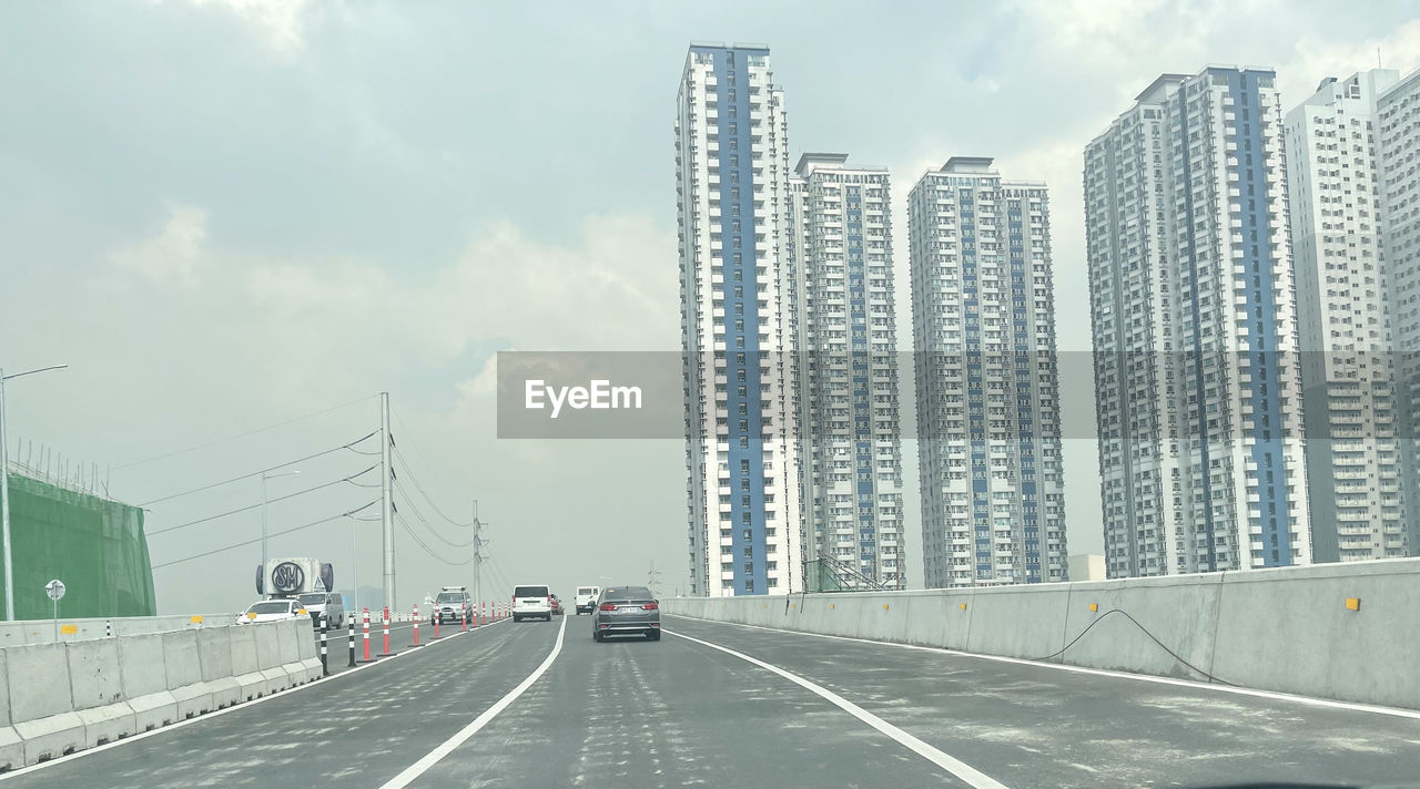 ROAD BY BUILDINGS IN CITY AGAINST SKY