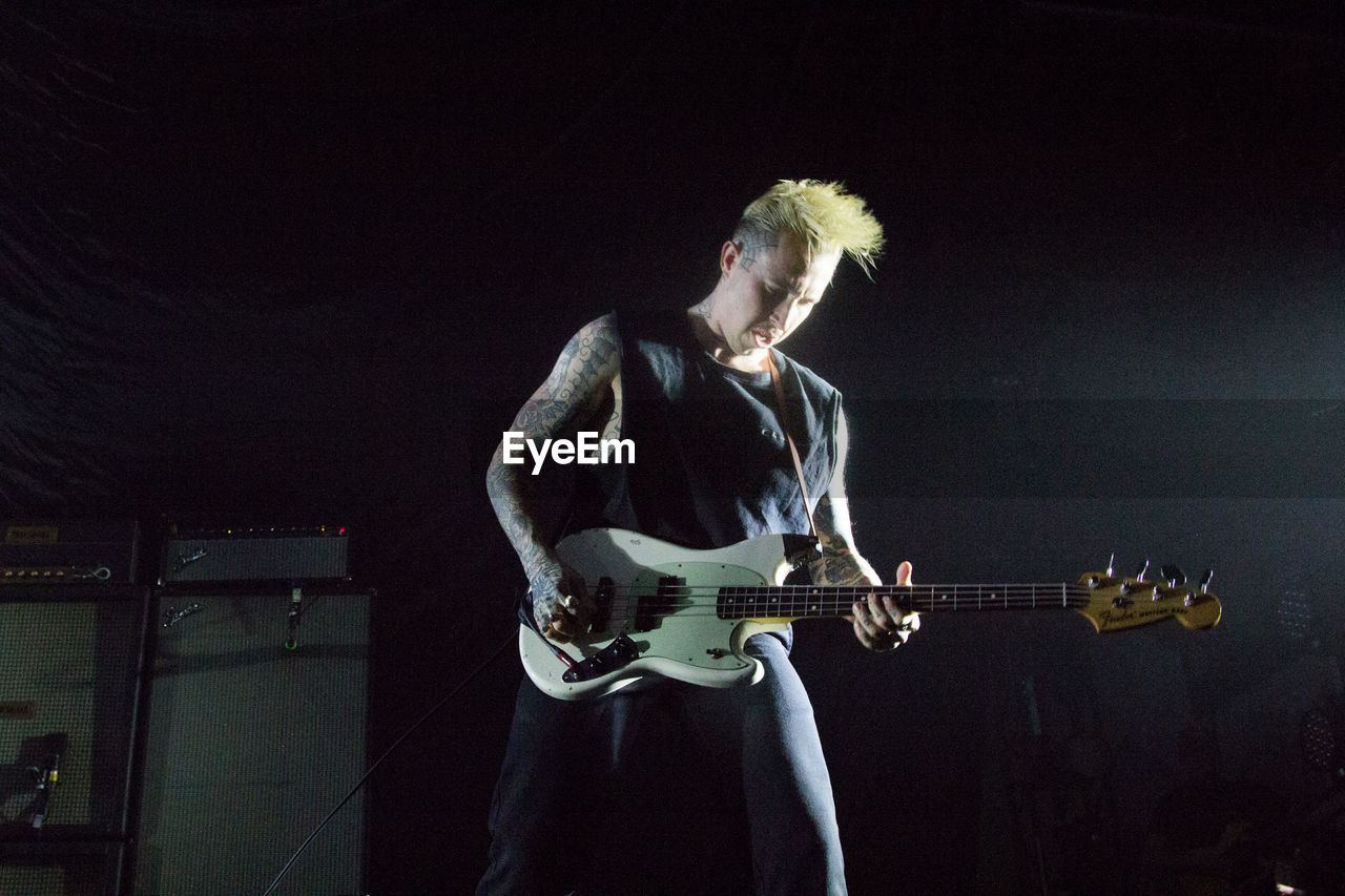 FULL LENGTH OF MAN PLAYING GUITAR ON STAGE