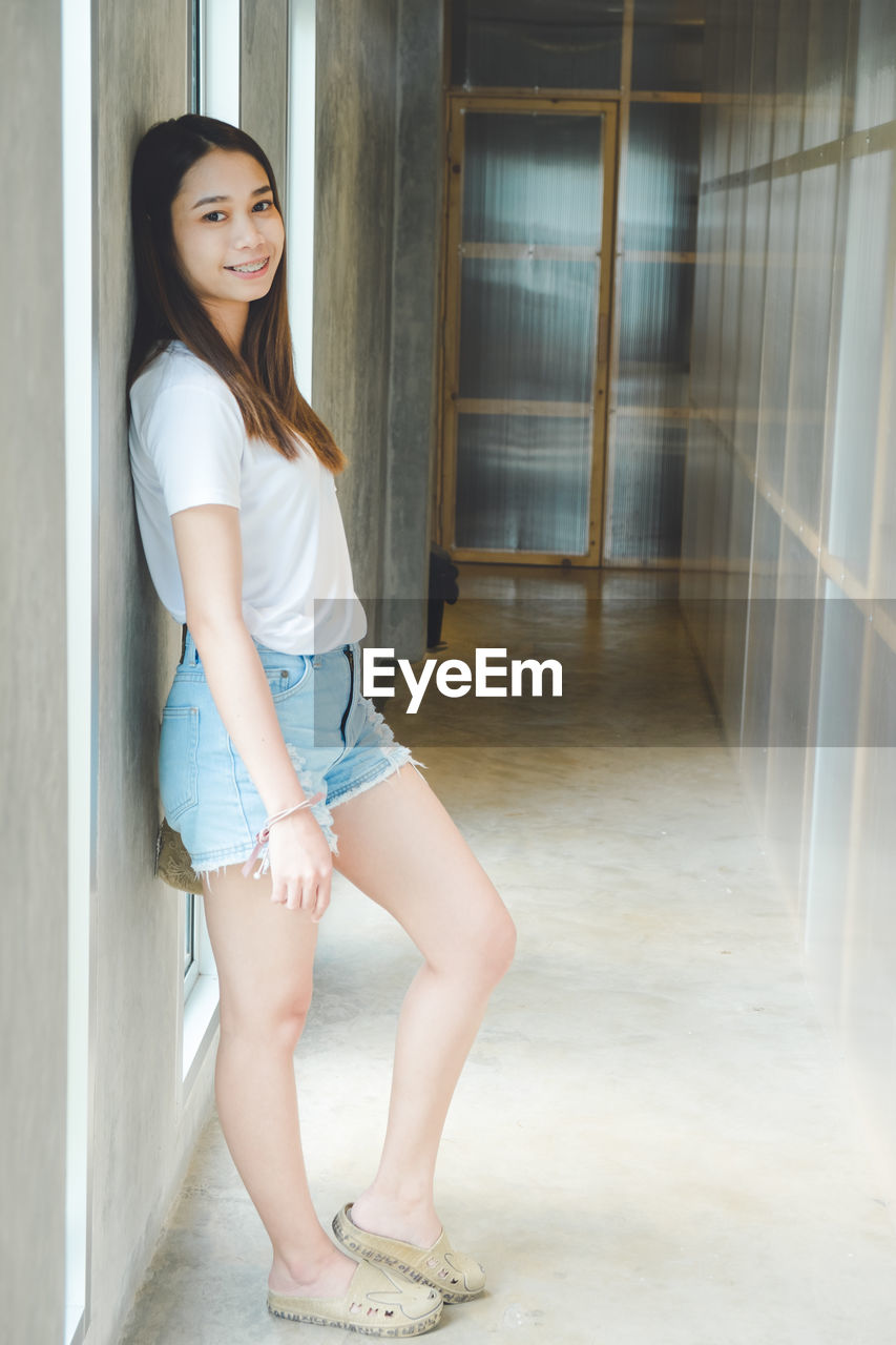 Portrait of smiling young woman standing in corridor