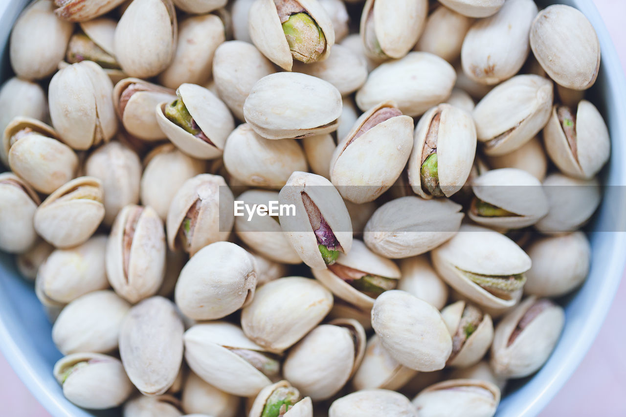 Pistachio in shell in bowl on pink background