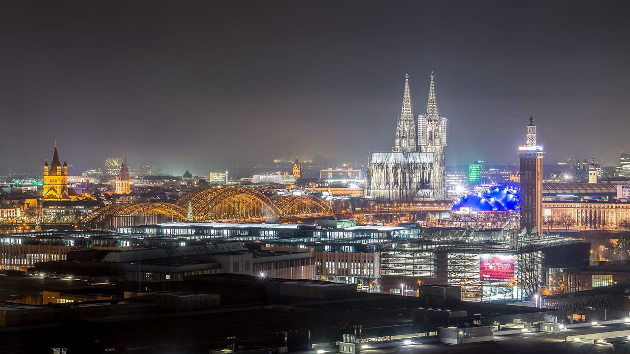 Illuminated cologne cathedral in city against sky at night