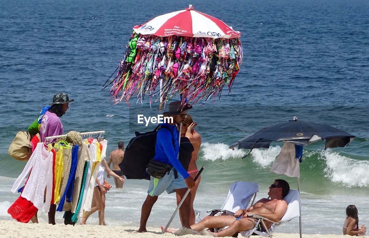 PEOPLE ON BEACH WITH UMBRELLAS ON SEA