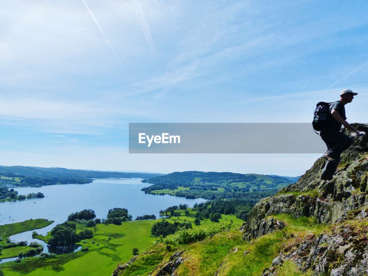 Scenic view of mountains with man on rock against sky