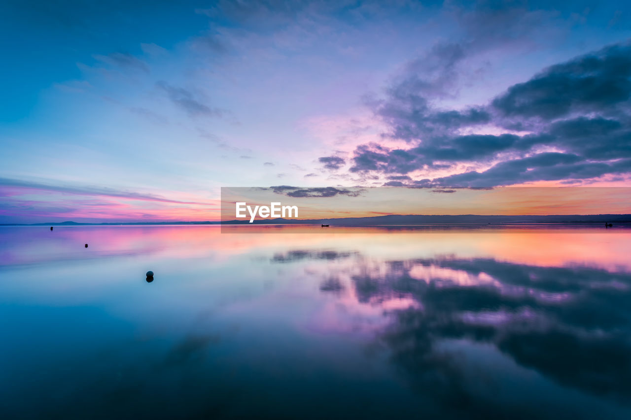 Scenic view of calm lake against sky during sunset