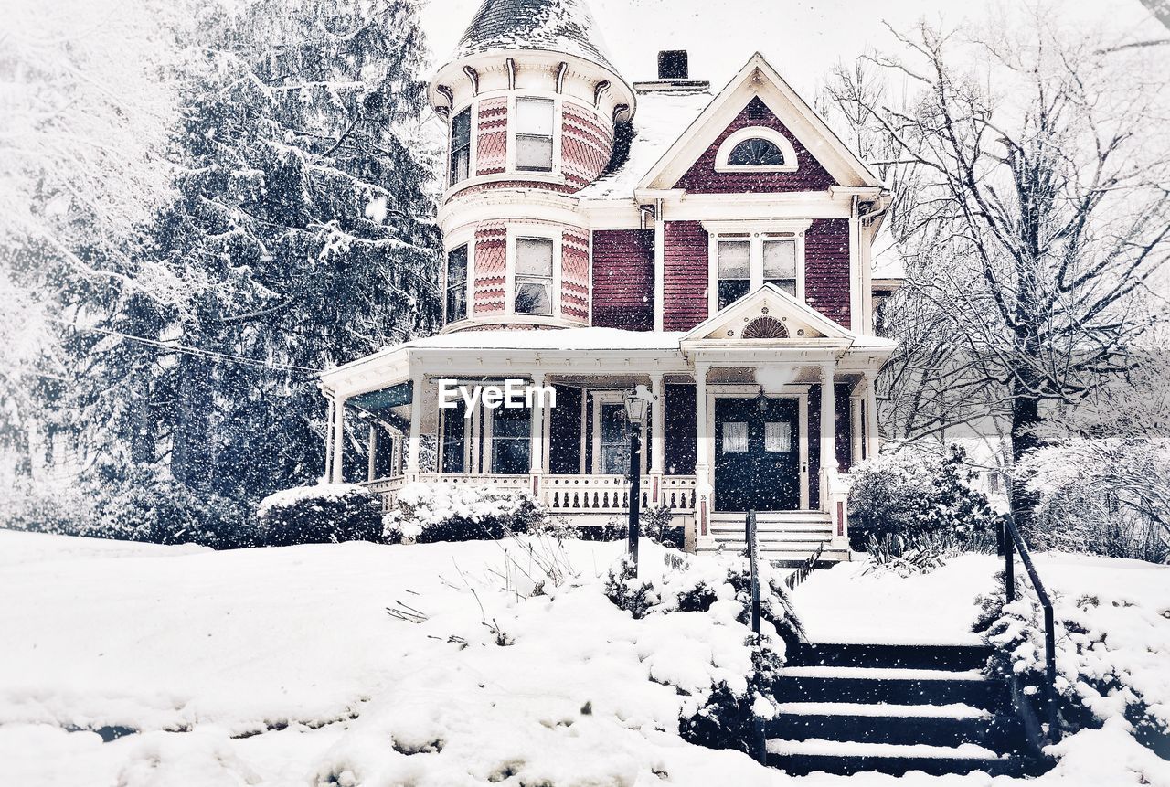 SNOW COVERED HOUSE BY TREES ON FIELD