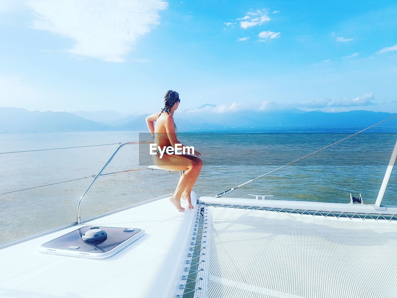 Woman sitting on boat deck against sky