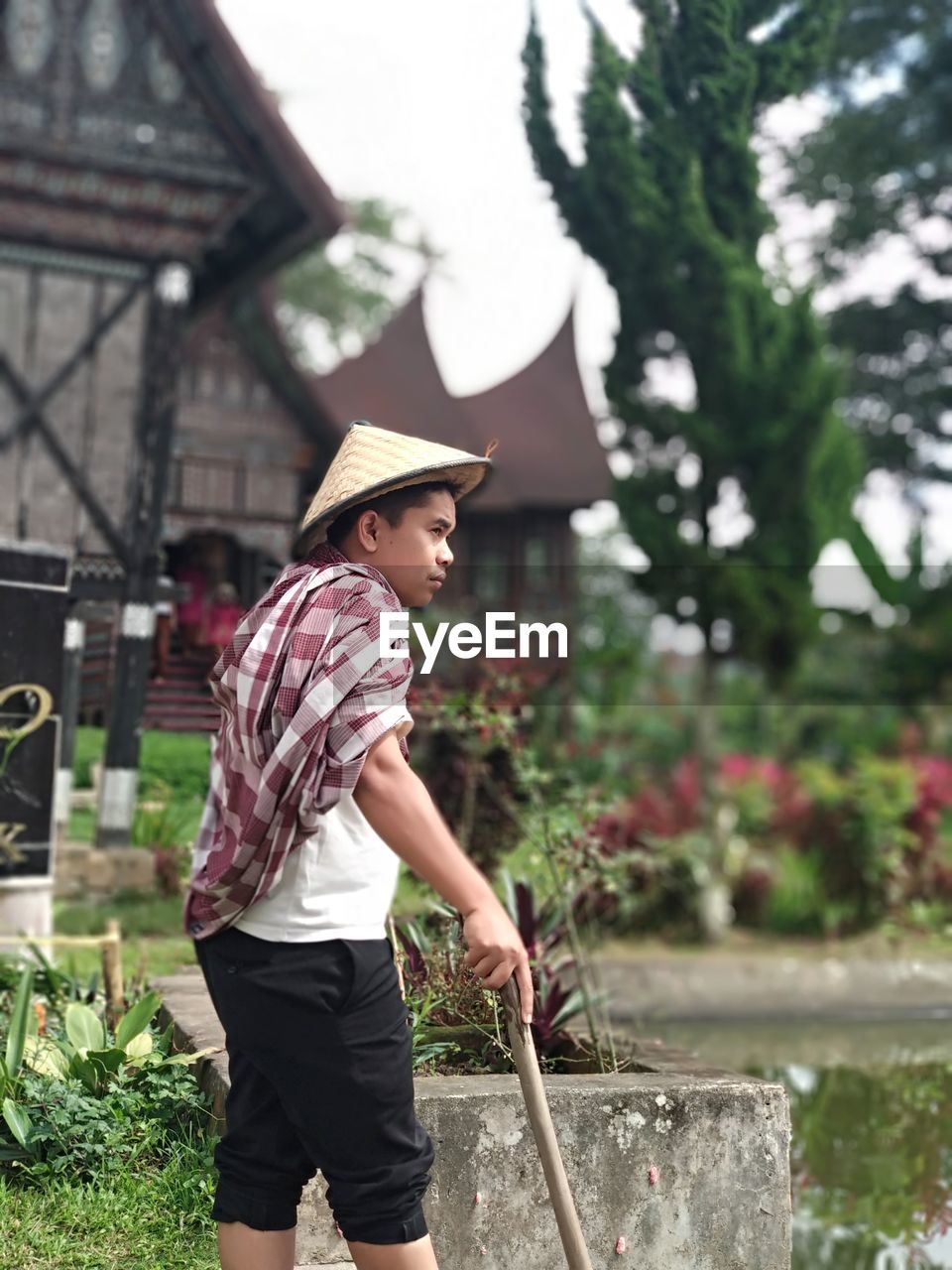 Man wearing asian style conical hat while standing on field