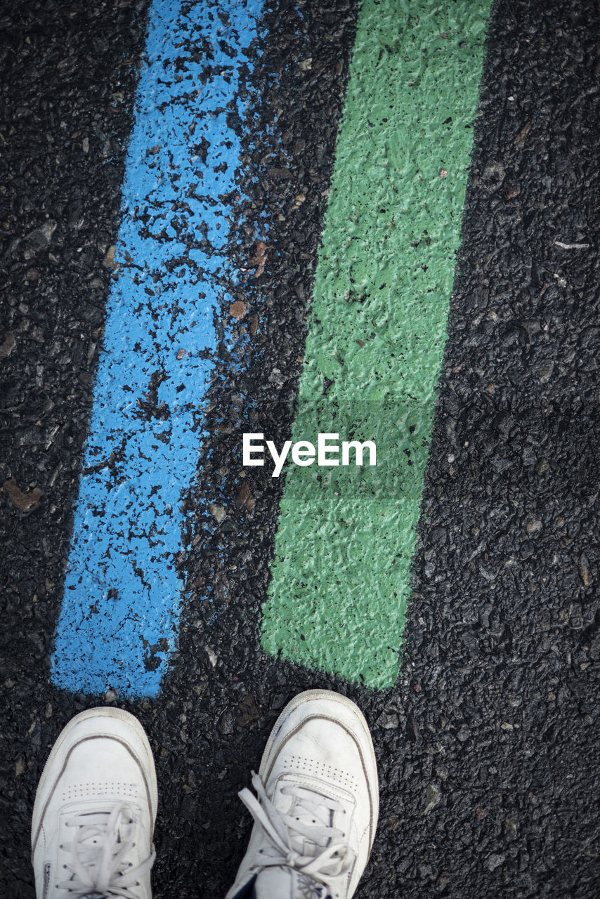 LOW SECTION OF PERSON STANDING ON ROAD BY STREET