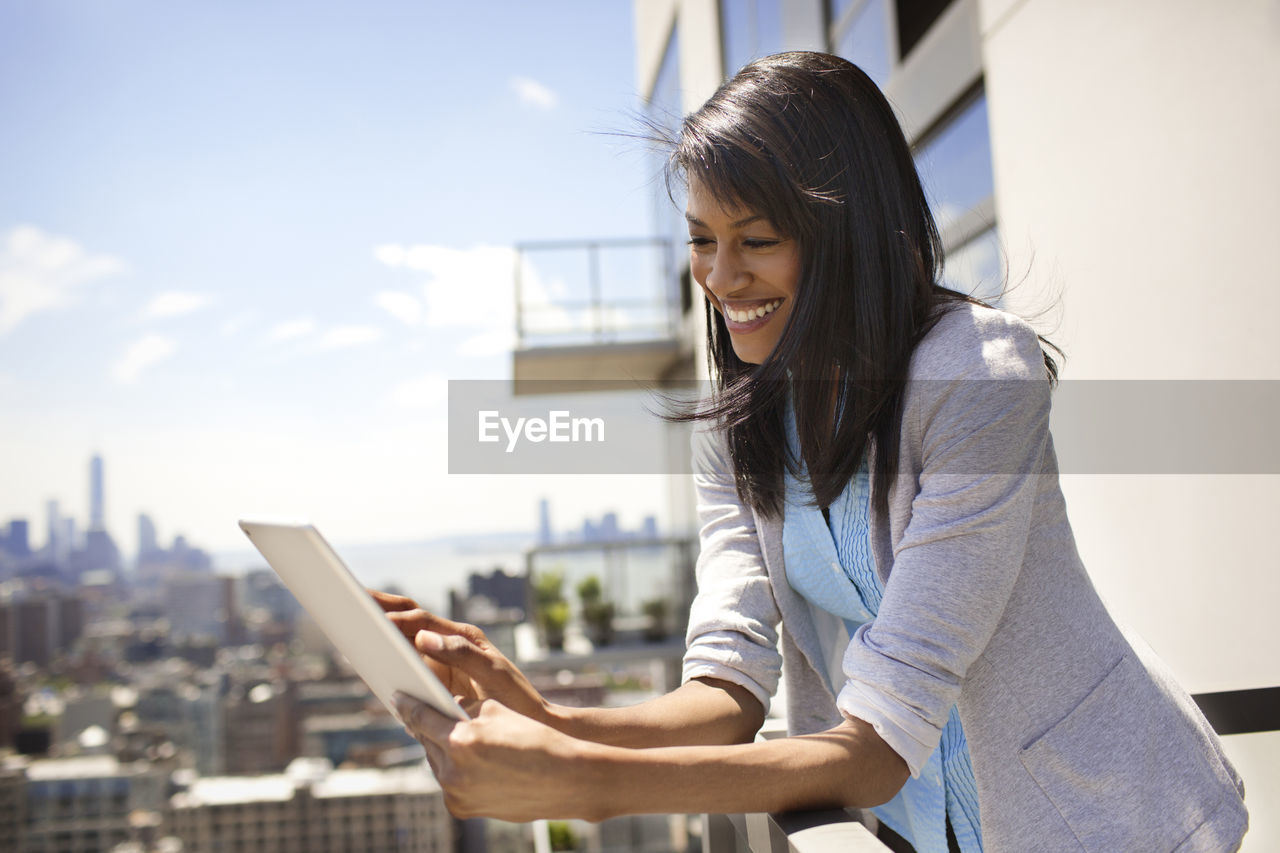 Low angle view of businesswoman using tablet computer in office balcony