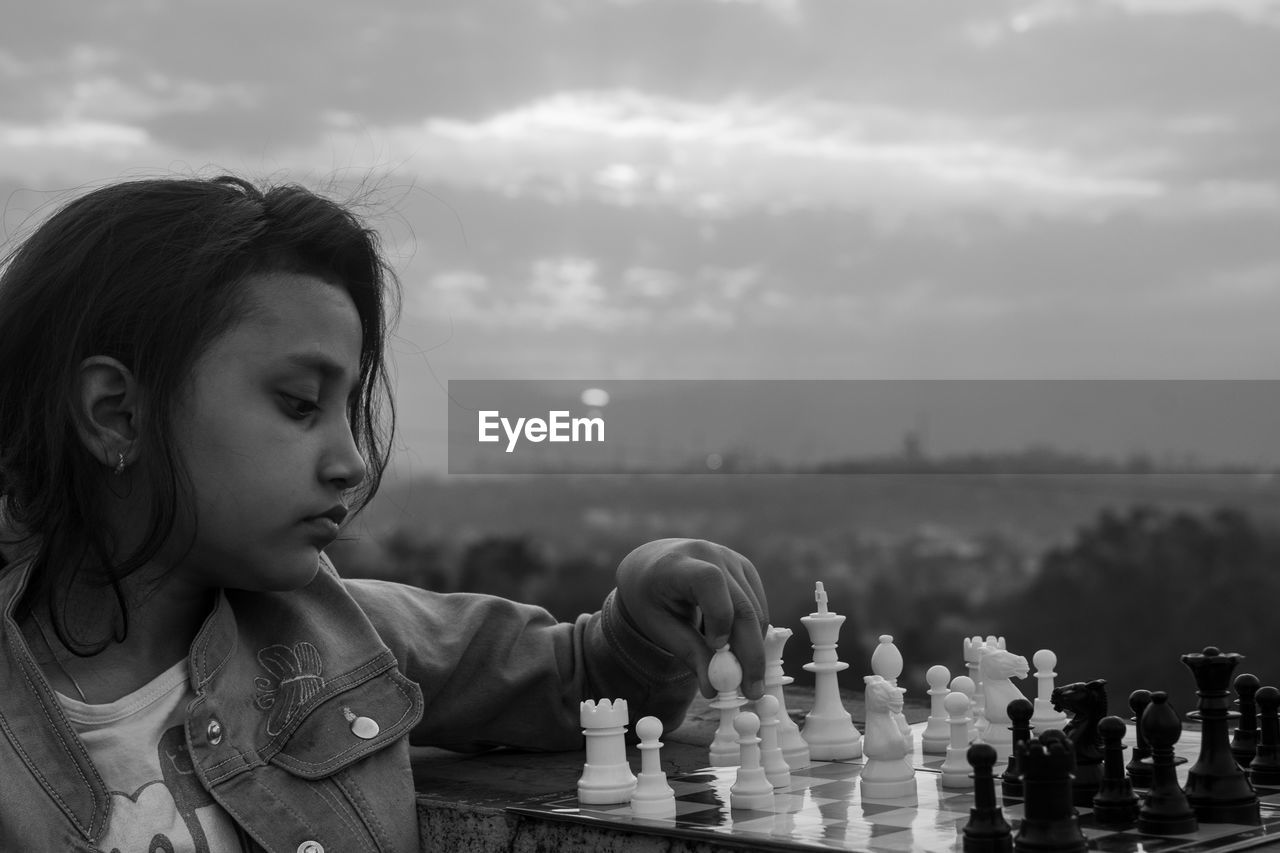 Close-up of young woman looking away against sky