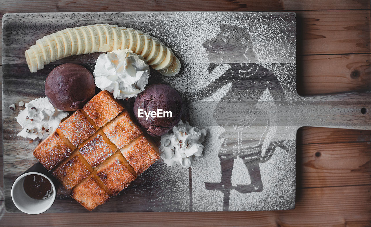 HIGH ANGLE VIEW OF ICE CREAM ON WOODEN TABLE