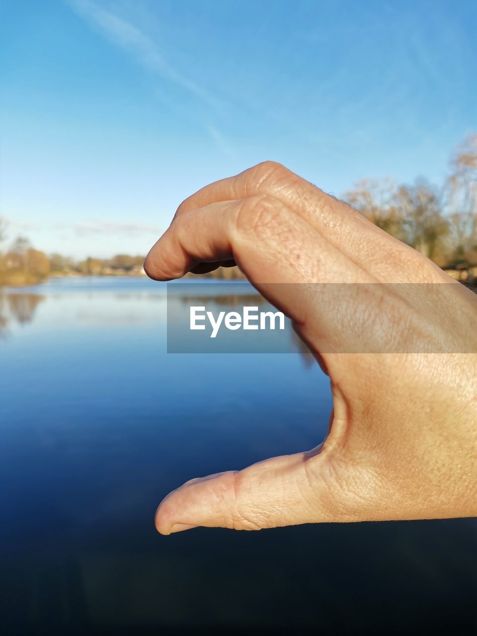 Close-up of hand against sea and sky