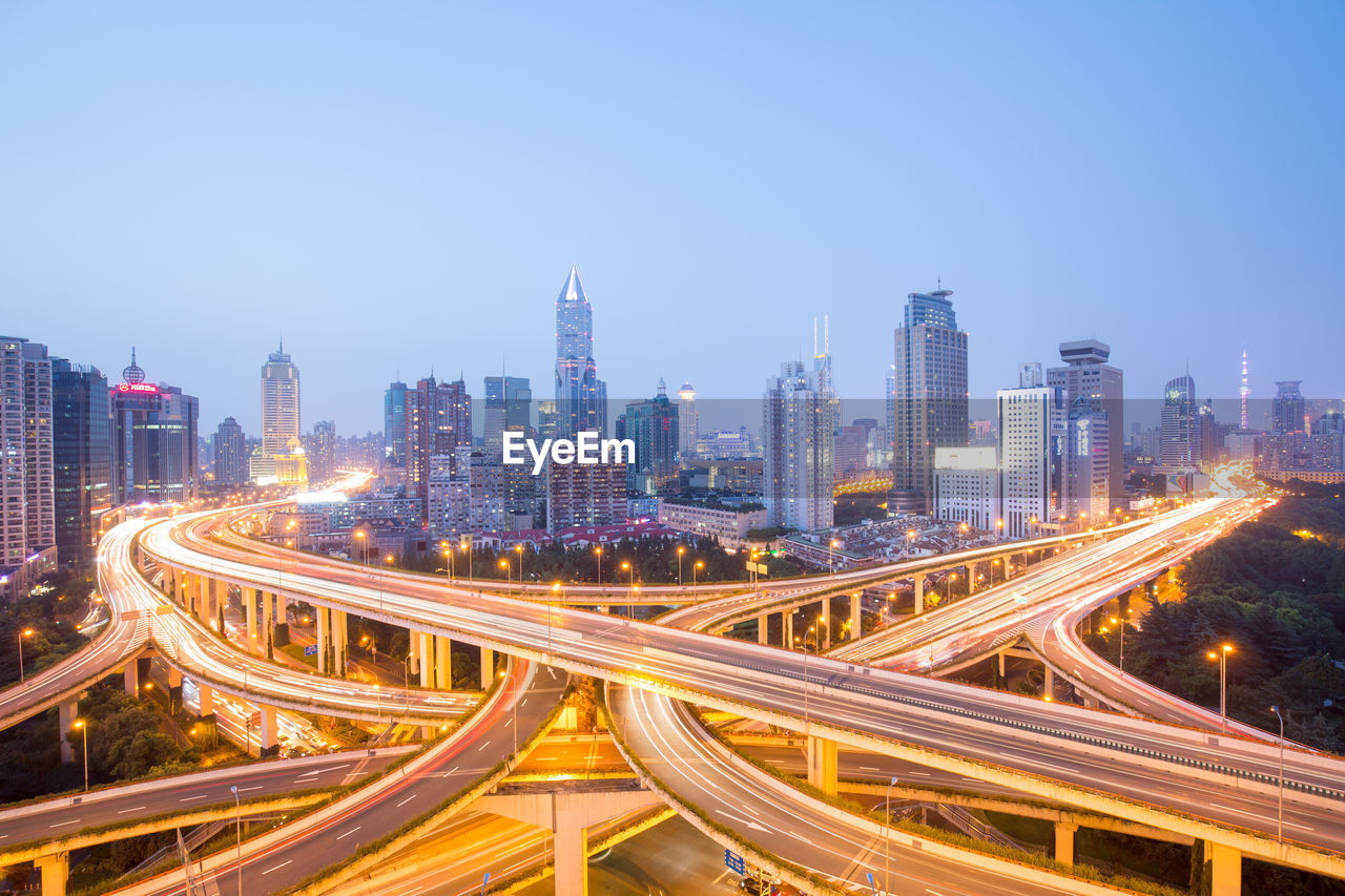 High angle view of light trails on road amidst buildings in city against sky