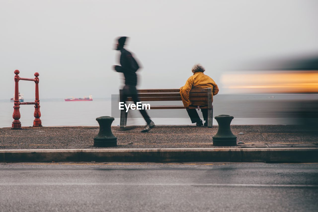 Blurred motion of man jogging on promenade in city