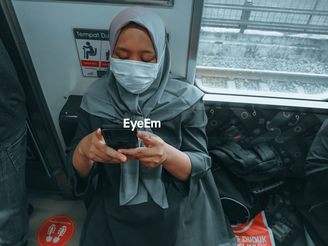 Woman using mobile phone while sitting in train