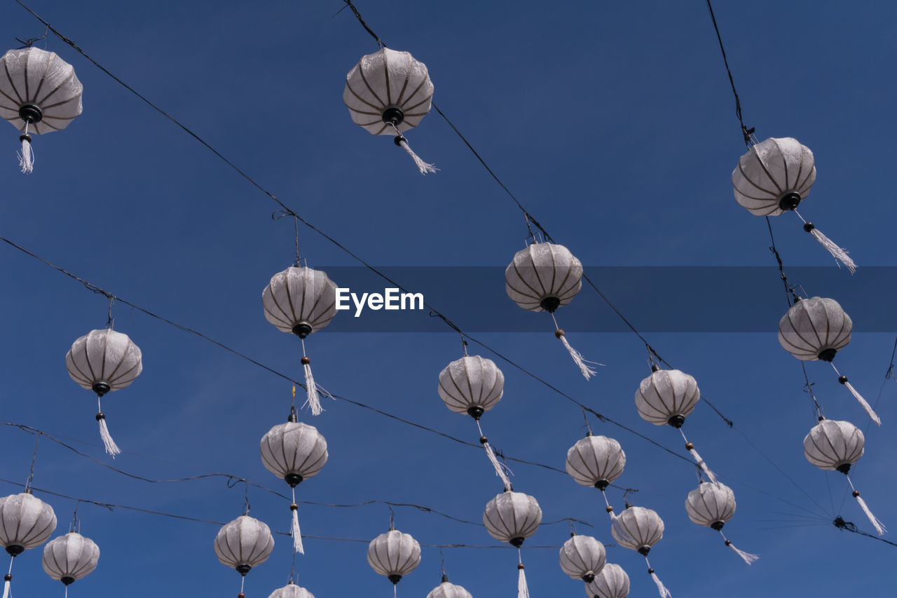 LOW ANGLE VIEW OF LIGHTING EQUIPMENT HANGING AGAINST CLEAR BLUE SKY